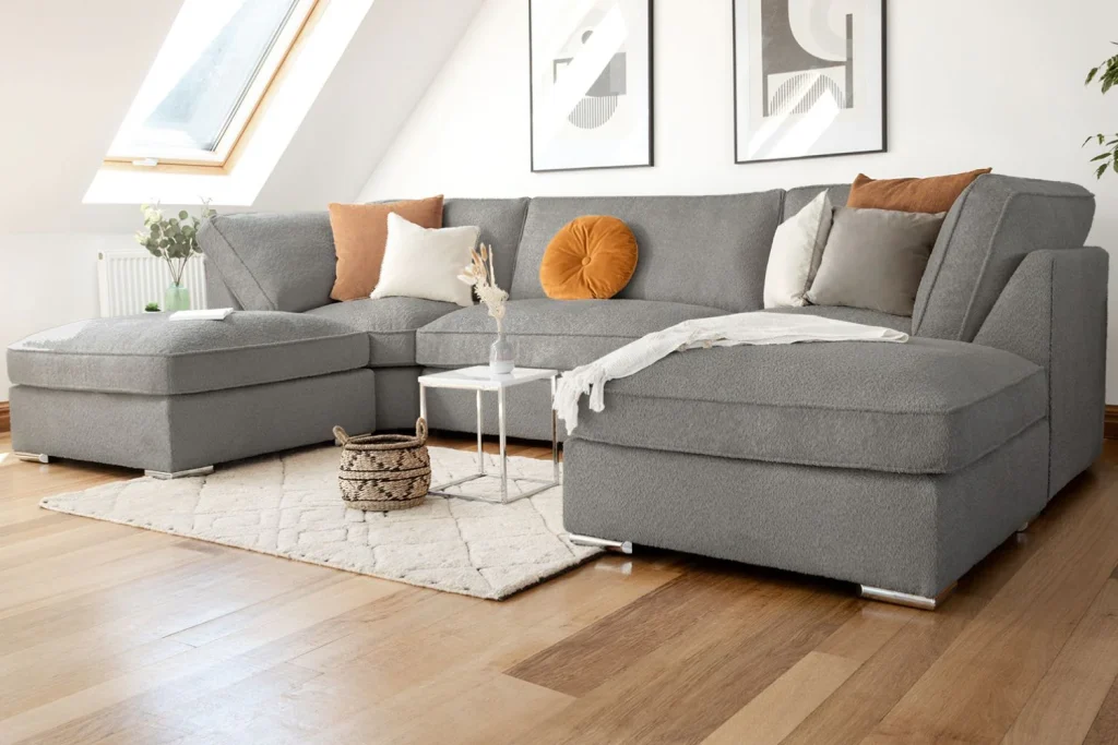 Gray sectional sofa on beige carpet with accent pillows and wooden coffee table in a modern living room.