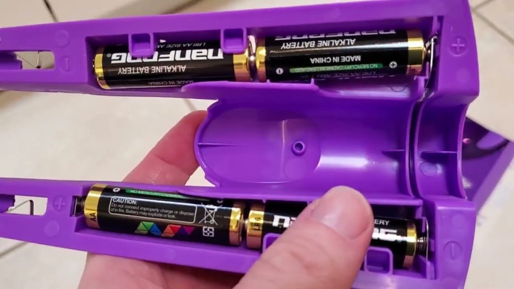 Close-up of a purple Swiffer Power Mop battery compartment showing two AA alkaline batteries installed.