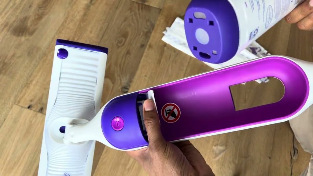 Hand inserting a cleaning solution bottle into the Swiffer Power Mop compartment on a wooden floor.