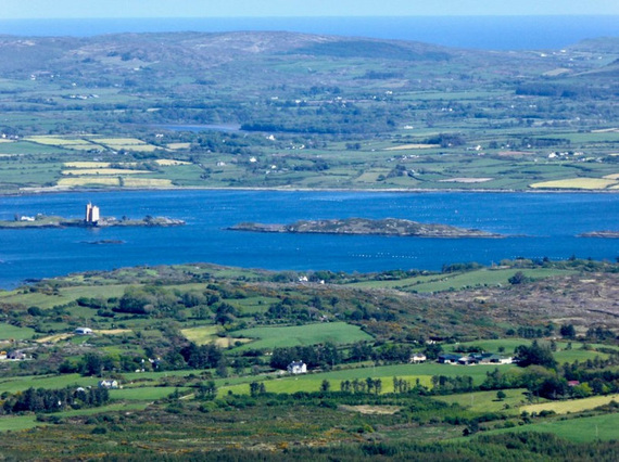Aerial view of Kilcoe Castle on its island in Roaringwater Bay, surrounded by green fields and blue water