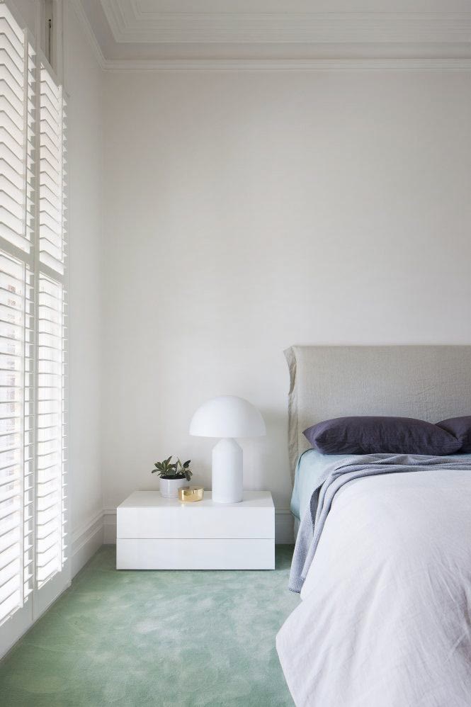 Boho green bedroom with trailing plants, macrame wall hangings, and a rattan chair