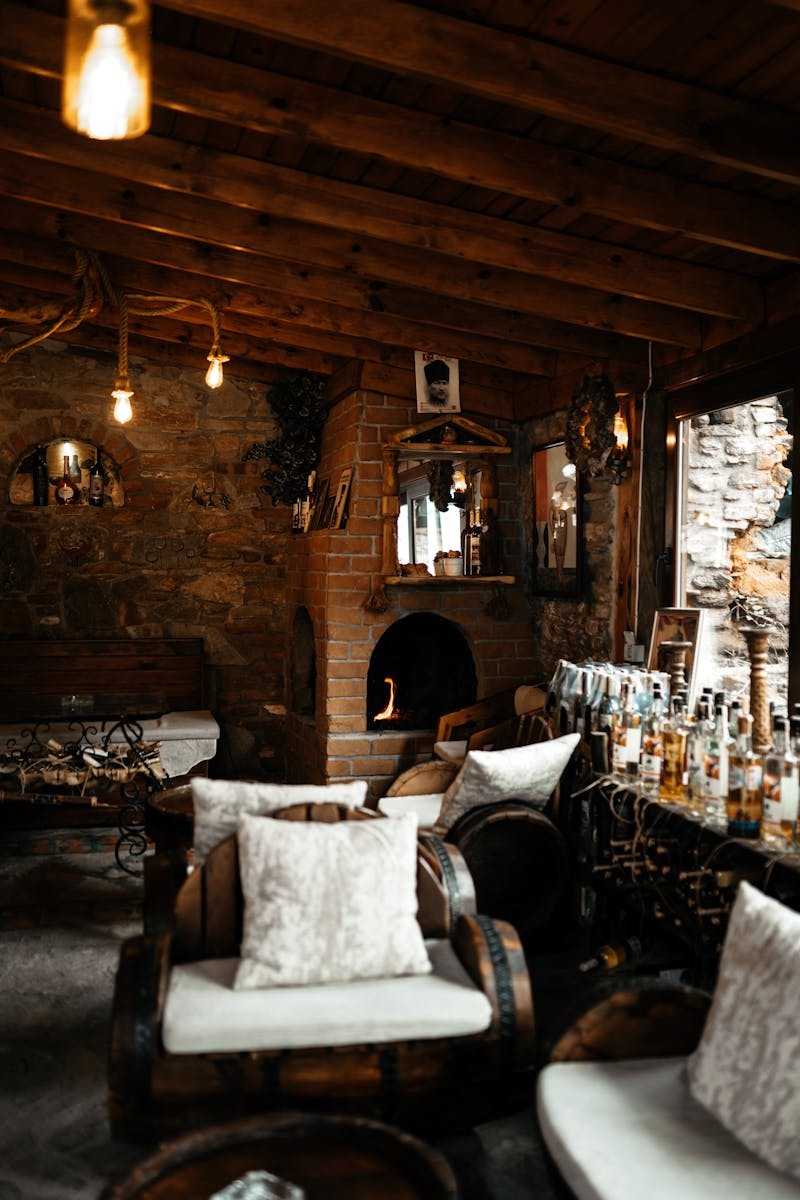 Cozy cottage interior with stone fireplace, warm lighting, bohemian decor, and rustic wooden accents