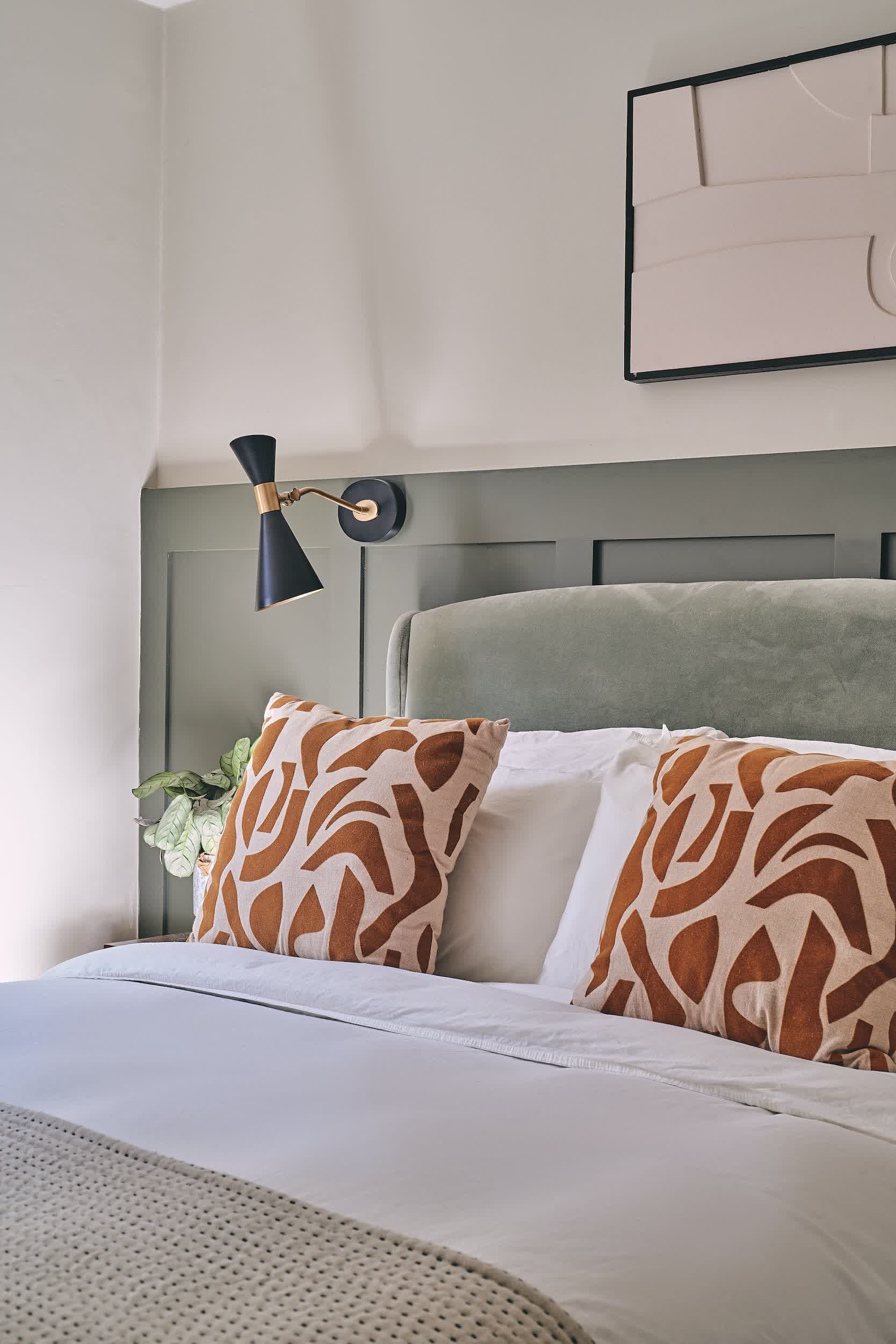 Dark green bedroom walls complemented by warm walnut furniture and brass table lamps