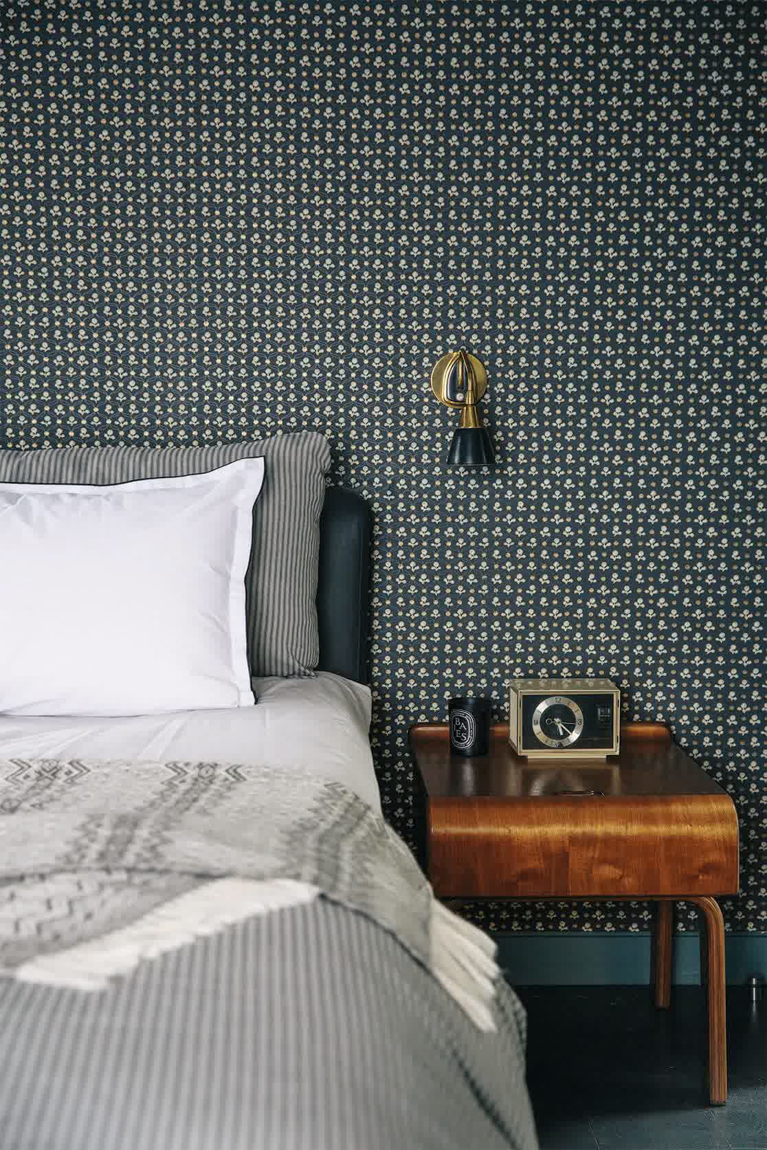 Dark green bedroom with gold-framed mirror and marble-topped nightstand creating a luxurious feel