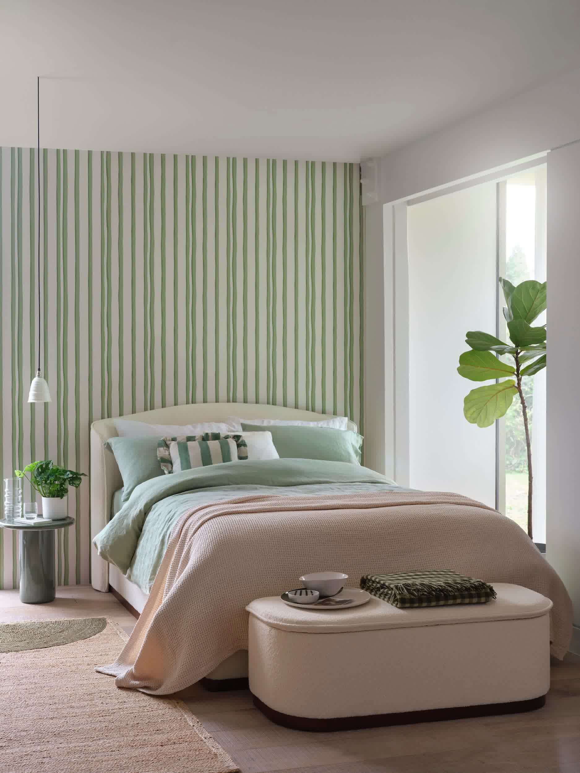 Deep green bedroom with a velvet upholstered bed frame and rich layered textures