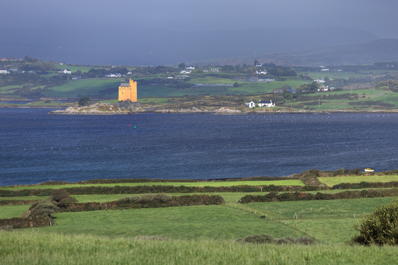 Exterior view of Kilcoe Castle, a terra-cotta colored medieval fortress on a rocky island in Roaringwater Bay, West Cork, Ireland