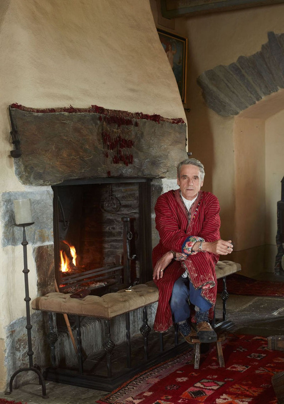 Guest bedroom in Kilcoe Castle with a large bed, exposed wooden beams, woven wickerwork ceiling, and medieval stone fireplace