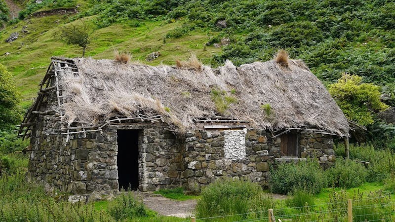 Historic Irish stone cottage with thatched roof in lush countryside