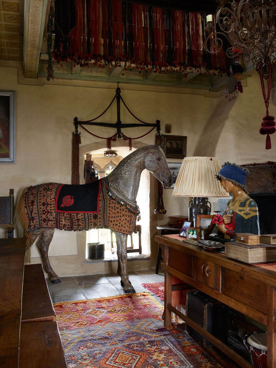 Interior detail of Kilcoe Castle showing the life-size wooden horse, chandelier, gallery above, tapestries, and vibrant rug