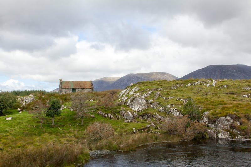 Irish stone cottage in County Wicklow countryside, surrounded by rolling hills, a river, and rocky green landscape