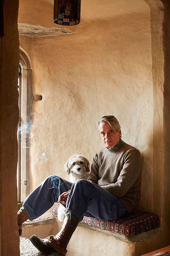 Jeremy Irons sits with his dog Smudge in an arched stone nook inside Kilcoe Castle, relaxed amid warm textured walls