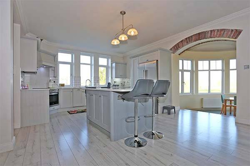 Kitchen of Niall Horan's Mullingar estate with white cabinetry, central island with bar stools, pendant lighting, and open-plan design leading to the dining area