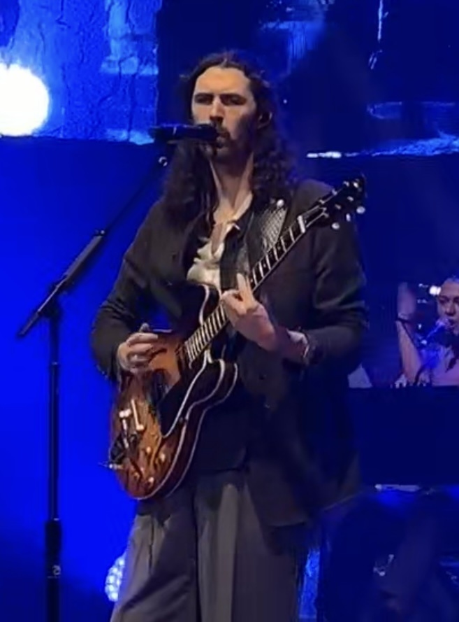 Musician Hozier (Andrew Hozier-Byrne) performs live on stage with guitar under blue lighting