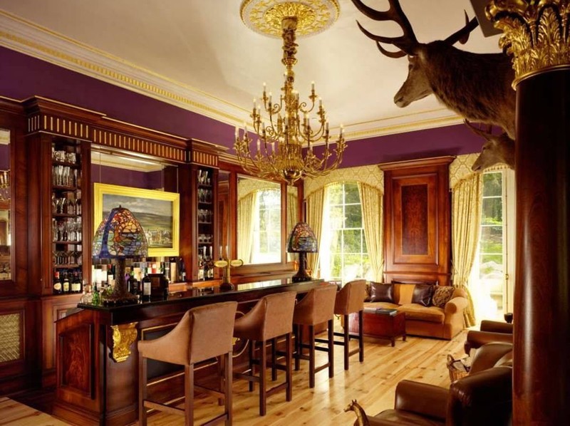 Opulent bar area in Castlehyde House with wood paneling, gilded chandelier and leather seating