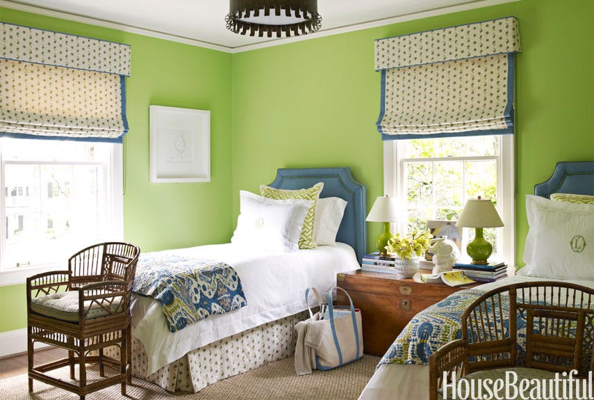 Sage green bedroom walls paired with natural oak bedside tables and layered white linen bedding