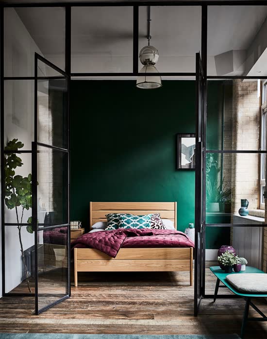 Sage green bedroom with soft natural light filtering through sheer curtains onto a linen-covered bed