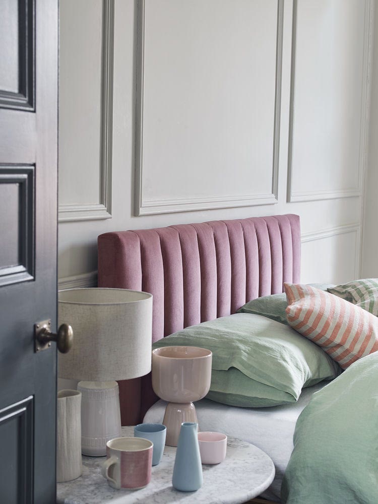 Soft muted green bedroom featuring a boucle upholstered bed and textured neutral cushions