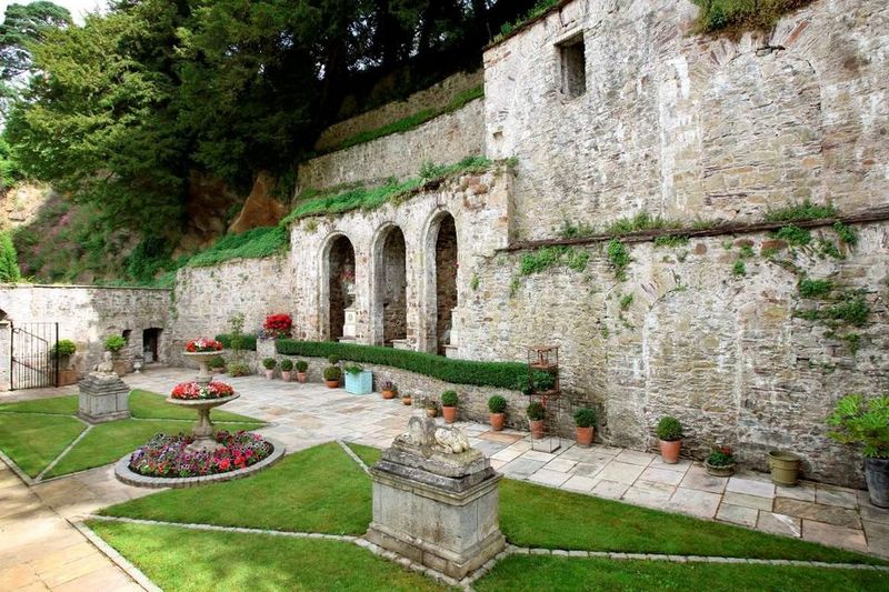 Stone courtyard of Castlehyde House with central fountain, manicured lawn and arched openings