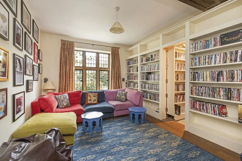 Interior design of Liam Gallagher's house showing a private library with floor-to-ceiling wooden bookshelves and historic ceiling beams