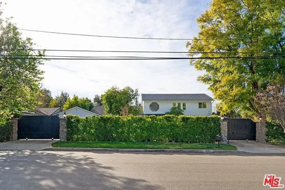 Tom Segura's Austin lakefront mansion gated entry with hedge, driveway, and modern architecture.